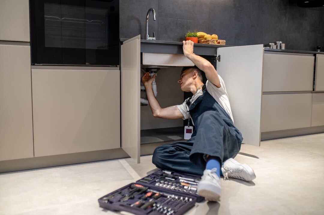 household-repair-middle-aged-man-inspecting-pipe-touching-hand-sink-stylish-modern-kitchen_259150-58265